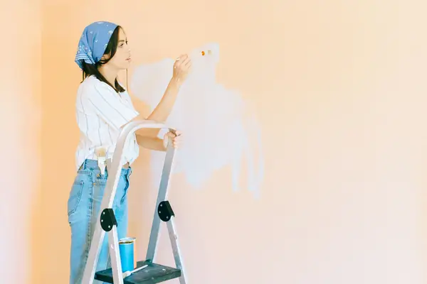 Interior painting in Greensboro: painter on a stepladder rolling a wall